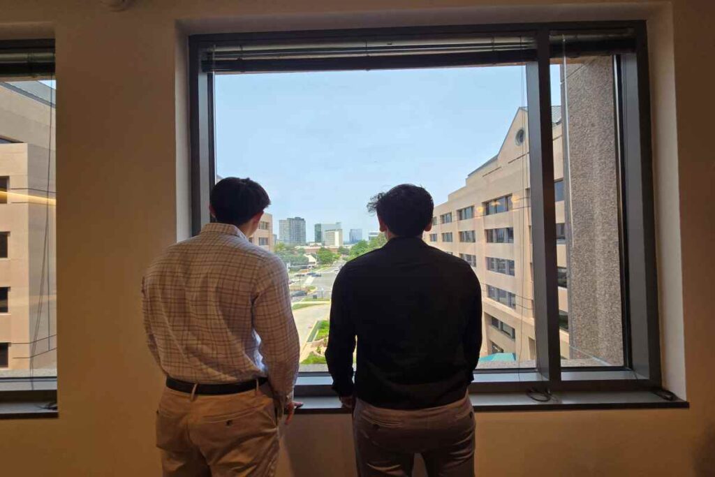 Two M&A Consultants Watching Building Outside Through Window