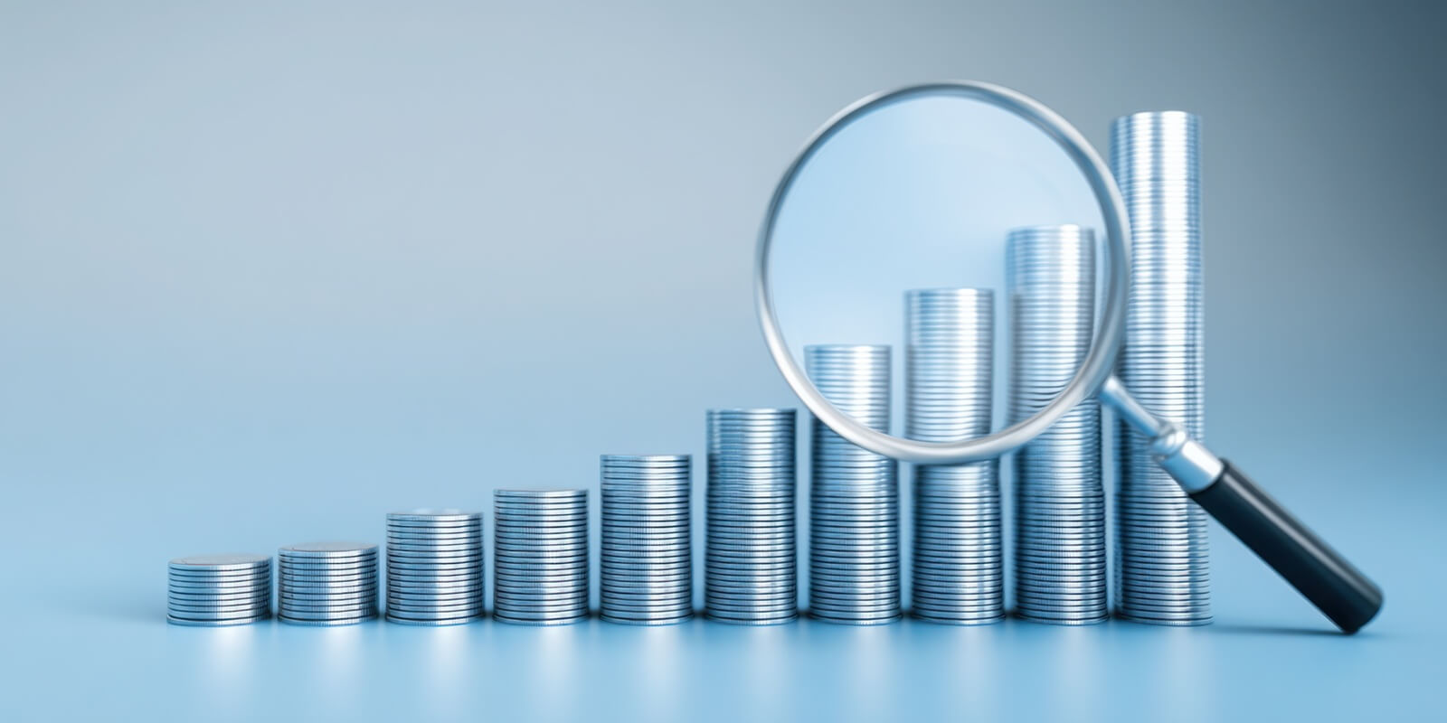 magnifying glass positioned over a stack of coins symbolizing cost forecasting and insight into financial future