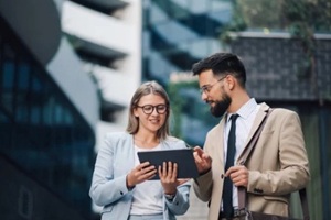 business people having informal meeting using digital tablet outside office building