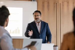 serious confident mature Indian business teacher giving seminar to students