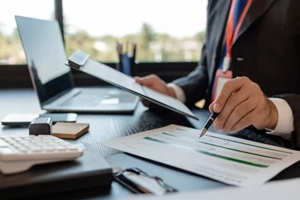 a businessman is reviewing accounting and financial statistics documents in his private office