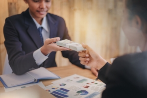 Businessman Passing Money to M&A Advisor on Table