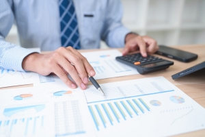 Businessman Analyzing TTM Numbers Report with Calculator